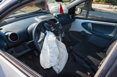 Interior of crashed car after accident with deflated airbags on road in city, sunny day clipart