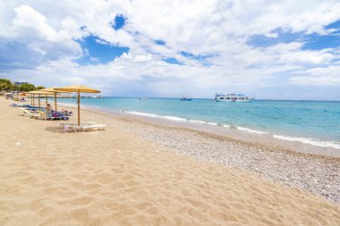 Stegna beach şemsiye, şezlong ve tekne içinde geçmiş (Rhodes, Yunanistan)