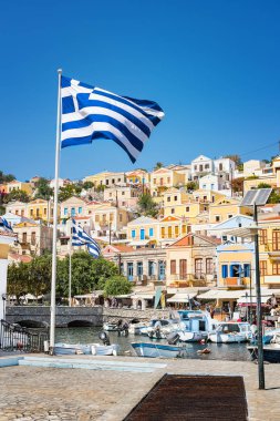Yunan bayrakları, tekneler ve liman şehri Symi (Symi Adası, Yunanistan renkli neoklasik evleri)