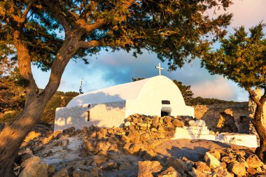 Yunan Ortodoks Kilisesi renkli görünümünü Monolithos kale kalıntıları üzerine inşa günbatımı sırasında (Rhodes, Yunanistan)