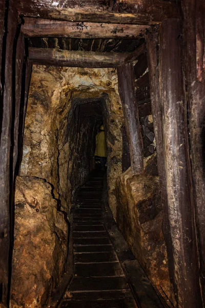 Old mine shaft with wooden timbering and person dressed in a min — Stock Photo, Image