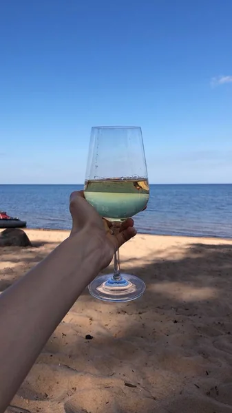 Glass of white wine in hand by the river