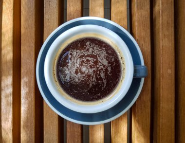 Ahşap bir masa üzerinde bir fincan sade kahve.