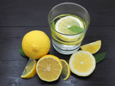 Küçük kase ve koyu ahşap zemin üzerine limon dilim taze limon suyu