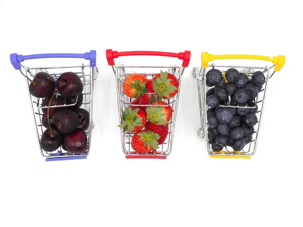 新鮮な夏の果物 チェリー いちご およびショッピング カートやトロリーは 白い背景で隔離のブルーベリー — ストック写真