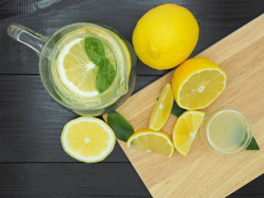 Küçük kase ve koyu ahşap zemin üzerine limon dilim taze limon suyu