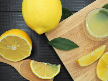 Küçük kase ve koyu ahşap zemin üzerine limon dilim taze limon suyu