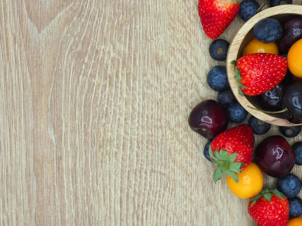 Fresh summer fruits, Cherry, strawberry, cape gooseberry and blueberry in wooden plate isolated on white background.