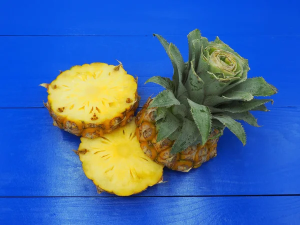 Fresh pineapple fruit with slices on blue wooden background