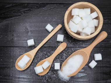 Ahşap kase ve küp şeker koyu ahşap zemin üzerine kaşıkla.