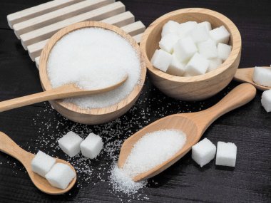 Ahşap kase ve küp şeker koyu ahşap zemin üzerine kaşıkla.