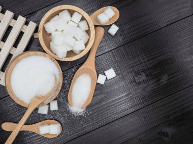 Ahşap kase ve küp şeker koyu ahşap zemin üzerine kaşıkla.