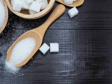 Ahşap kase ve küp şeker koyu ahşap zemin üzerine kaşıkla.