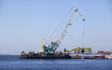 Denizde yüzer vinç bir mavna kum ile yükler