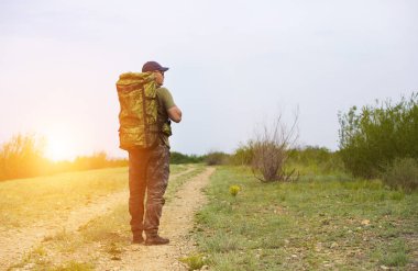 Bir gezgin bir sırt çantası ile yol boyunca yürüyüş