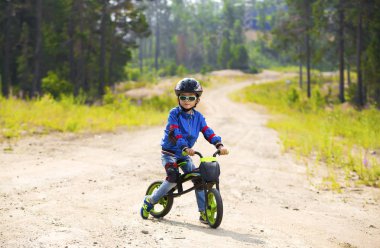 Mutlu bir çocuk kask ve gözlük bir bisiklet sürme