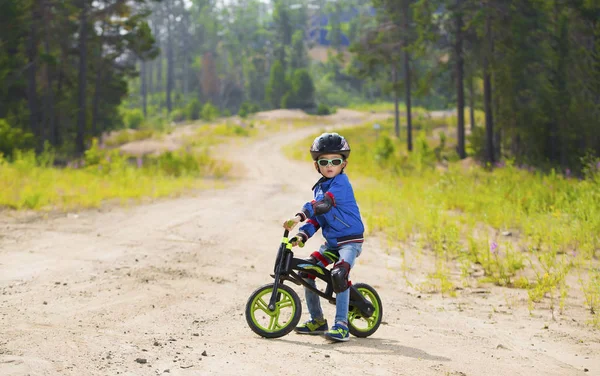 Mutlu bir çocuk kask ve gözlük bir bisiklet sürme