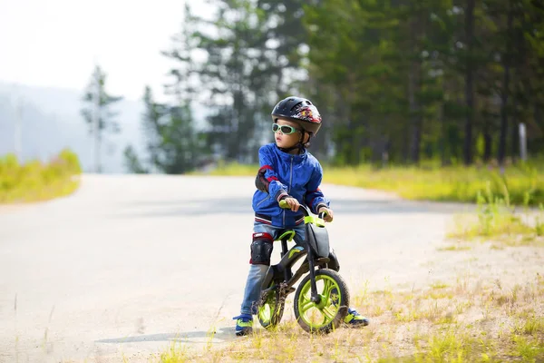 Mutlu bir çocuk kask ve gözlük bir bisiklet sürme