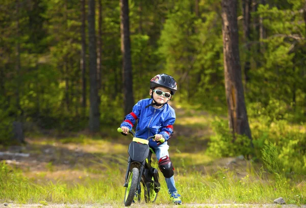 Mutlu bir çocuk kask ve gözlük bir bisiklet sürme