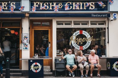 Londra, İngiltere - 22 Temmuz 2018: Poppie'nın Spitalfields, Londra, ünlü balık ve 1952'den beri hizmet veren chips Dükkanı içinde dışında bir bankta oturan insanlar. 