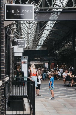 London, UK - July 22, 2018: People walking in Spitalfields Market, one of the finest surviving Victorian Market Halls in London with stalls offering fashion, antiques and food. clipart