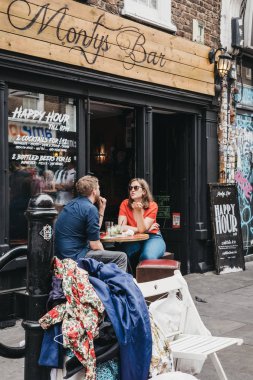Londra, İngiltere - 22 Temmuz 2018: Brick Lane, Londra, İngiltere'de en popüler turistik yerleri Monty'nin çubuğunun açık masalarda oturan insanlar.