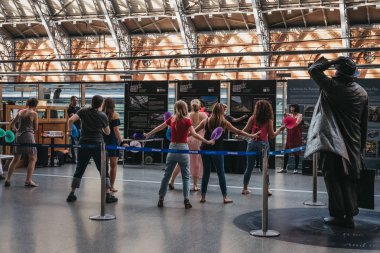 London, UK - July 26, 2018: People attending a retro dance event inside St. Pancras Station, London. St. Pancras is one of the largest railway stations in London and a home to Eurostar. clipart