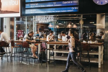Londra, İngiltere - 26 Temmuz 2018: onların tren kalkış kurulu St. Pancras İstasyonu içinde altında bekleyen bir kafede oturan insanlar Londra ve Eurostar evine bir en büyük tren istasyonları.