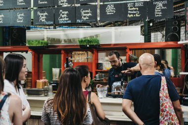 Londra, İngiltere - 24 Temmuz 2018: Borough Market bir piyasa ahır, hazırlama adam taze meyve suyu satın almak queuing insanlar, en büyük ve en eski gıda biri Londra'da pazarlar.