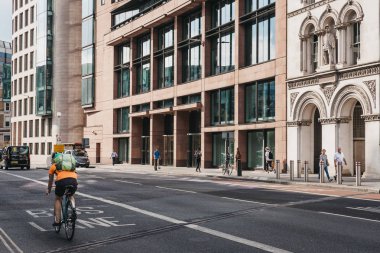 Londra, İngiltere - 24 Temmuz 2018: bisikletçi havada, modern bir ofis şehir Londra'nın, Londra'nın ünlü finans merkezi binası önünde otobüs şeridi.