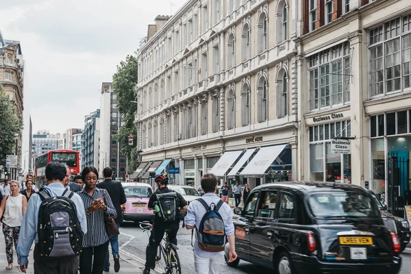 Londra, İngiltere - 24 Temmuz 2018: City, Londra, Londra'nın ünlü finans merkezi bir sokakta geçerken siyah taksi ile bir kaldırımda yürürken insanlar.