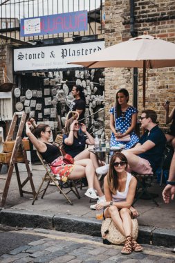 Londra, İngiltere - 22 Temmuz 2018: insanlar, Erza Caddesi üzerinde yere oturmuş, Columbia yol çiçek pazarı ziyaret ettikten sonra rahatlatıcı bir semt pazarı Doğu Londra'daki her Pazar günü açık mı.