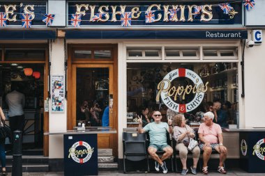 Londra, İngiltere - 22 Temmuz 2018: Poppie'nın Spitalfields, Londra, ünlü balık ve 1952'den beri hizmet veren chips Dükkanı içinde dışında bir bankta oturan insanlar.