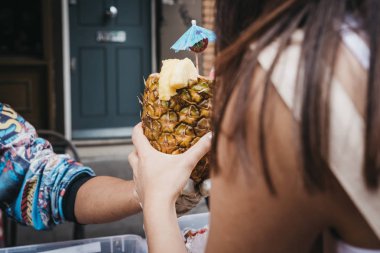 Taze ananas, Portobello Road Market, Londra, İngiltere'de bir pazar ahır içinde tropikal içki satın alma kadın hizmet.