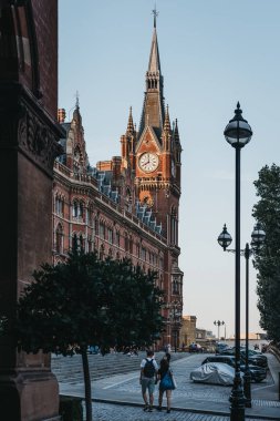 London, UK - July 26, 2018: People walking towards iconic building of St. Pancras Renaissance Hotel, London, a five-star hotel in located in a 1873 Gothic Revival building in St. Pancras station. clipart