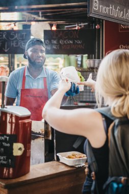 Londra, İngiltere - 17 Eylül 2018: Kadın koleksiyonu yiyecek sipariş Borough Market, bu teslim personel Northfield kasaplık tribünde de. Borough Market, Londra, İngiltere'de en büyük pazarlarından biri.