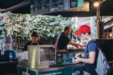 Londra, İngiltere - 17 Eylül 2018: adam, semt pazarında Boston sosis standından yemek siparişi en büyük ve en eski gıda biri Londra'da pazarlar.
