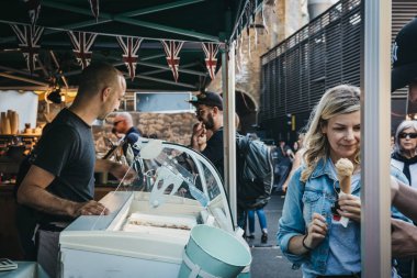 London, UK - September 17, 2018: People buying ice-cream from Greedy Goat market stand in Borough Market, one of the largest and oldest food markets in London. clipart