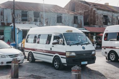Bridgetown, Barbados - June 26, 2018: Private white mini buses parked at the outdoor bus terminal in Bridgetown. Bridgetown is the capital of Barbados and a port city on the islands southwest coast clipart