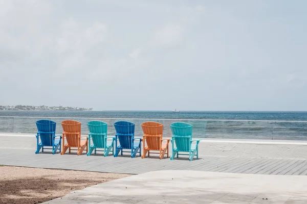 彩色甲板椅的后景色排列在一排由海 — 图库照片