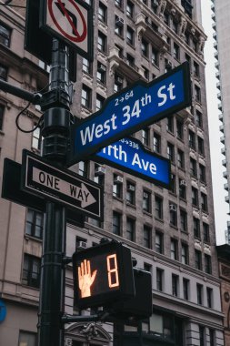 Köşede bir lamba yayında sokak adı ve yol işaretleri Fifth Avenue ve Batı 34th Street Manhattan, New York, ABD.
