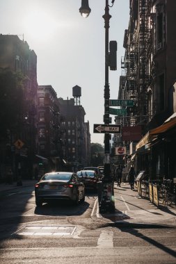 New York, USA - May 29, 2018: People walking on a street in Lower East Side, New York, USA, during golden hour.  New York is one of the most visited cities in the world. clipart