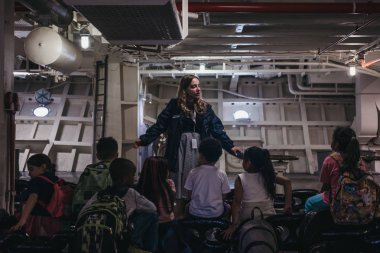 New York, ABD - 1 Haziran 2018: okul grubu Intrepid deniz ve Hava Müzesi, New York, ABD bir Amerikan askeri ve denizcilik tarihi müze içinde bir tur sırasında belgili tanımlık delâlet dinleme.