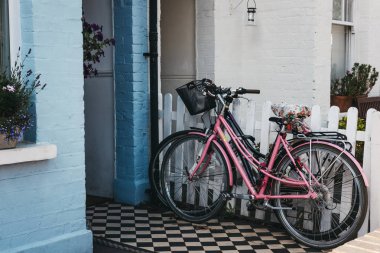 Londra, İngiltere - 1 Ağustos 2018: Onun ve onun önünde Barnes, varlıklı bir yerleşim bölgesi olan Londra köy atmosferi için ünlü bir pastel mavi evde üzerinde bisiklet.