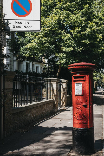 London, UK - August 1, 2018: Iconic red postbox belonging to Royal Mail on a street in London. Royal Mail is a postal service and courier company in the United Kingdom, originally established in 1516.