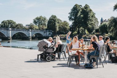 Londra, İngiltere - 1 Ağustos 2018. Oturma ve Thames Nehri Richmond, Güney-Batı Londra çok sayıda park ve açık alanlar için ünlü bir banliyö kasabasında tarafından açık masalarında rahatlatıcı iki kişi.