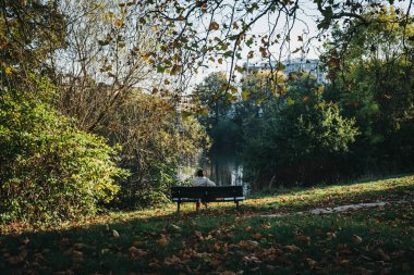 Londra, İngiltere - 27 Ekim 2018: bir bankta oturan, gölet Hampstead Heath tarafından rahatlatıcı kişi. Hampstead Heath 320 hektarlık bir Londra'nın en popüler açık alanlarda kapsar.