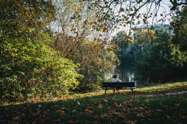 Londra, İngiltere - 27 Ekim 2018: bir bankta oturan, gölet Hampstead Heath tarafından rahatlatıcı kişi. Hampstead Heath 320 hektarlık bir Londra'nın en popüler açık alanlarda kapsar.