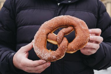 Kimliği belirsiz kişi giyen kış ceket taze tutan donuts simit elinde yaptı..
