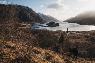 Glenfinnan, İskoçya - 17 Mart 2018: Glenfinnan, arka planda Glenfinnan Anıt'da yürüyüş insanlar. Anıt dikildi 1745 olduğunu ve İskoçya Milli güven tarafından bakım.